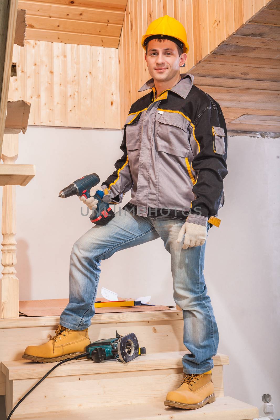 contractor standing on ladder and holding cordless drill by mihalec