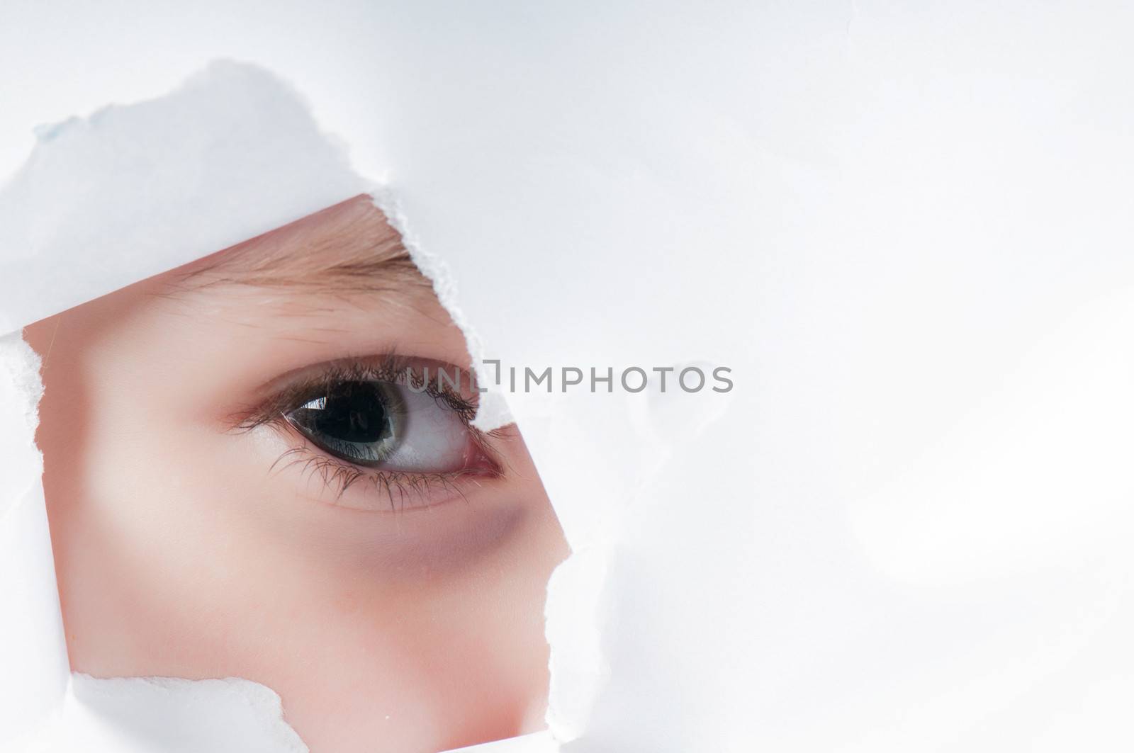 Child eye looking through a hole in paper by anytka