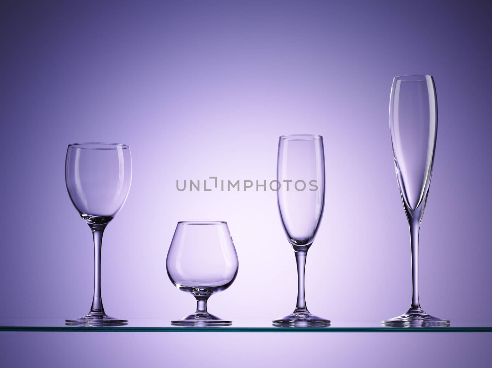 four empty wine glasses over purple background