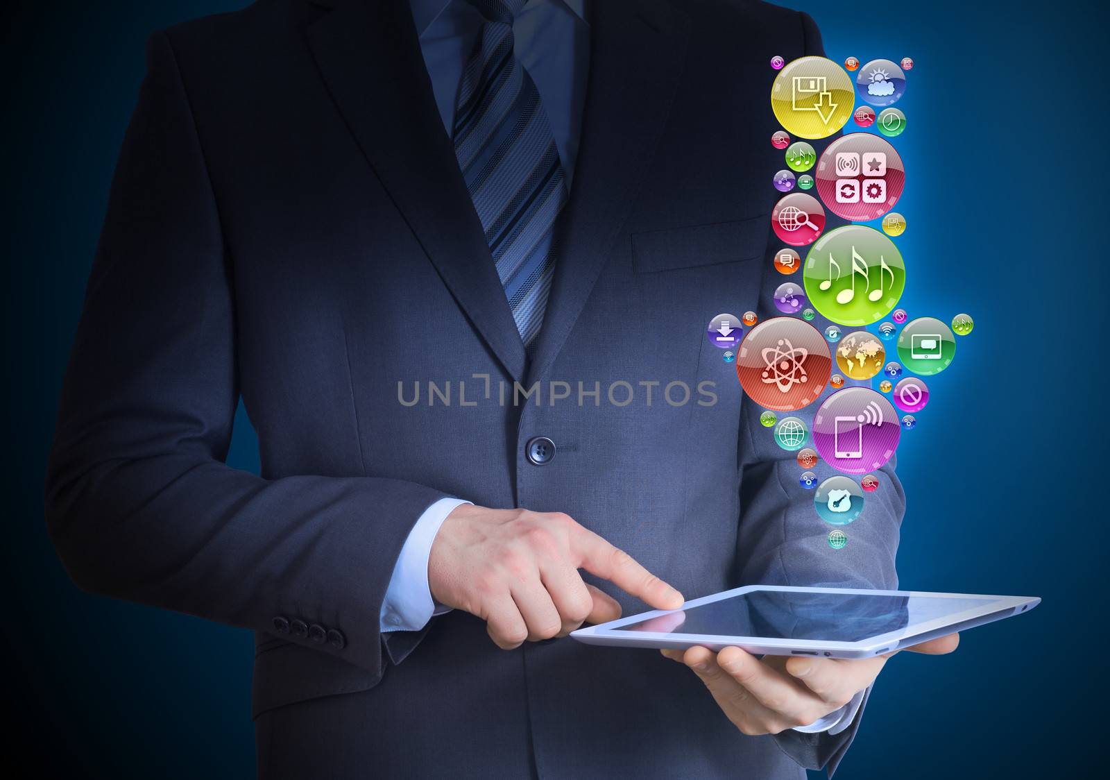 Businessman in a suit holding a tablet in his hands. Above the screen tablet application icons in the form of download icon