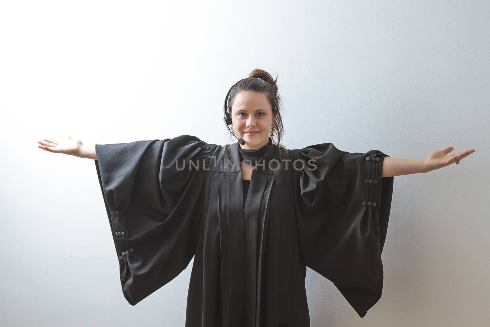 thirty something brunette woman wearing a preacher's toga opening her arm stretched as a cross