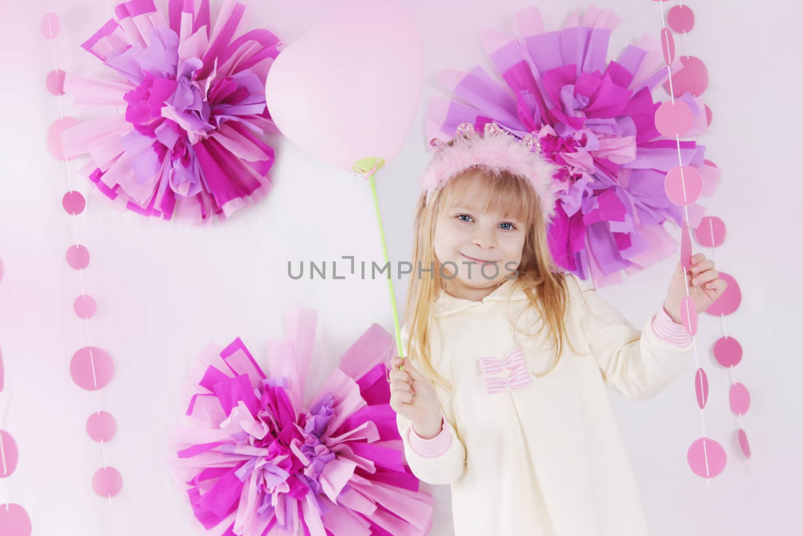 Happy little girl at pink decorated birthday party with balloon