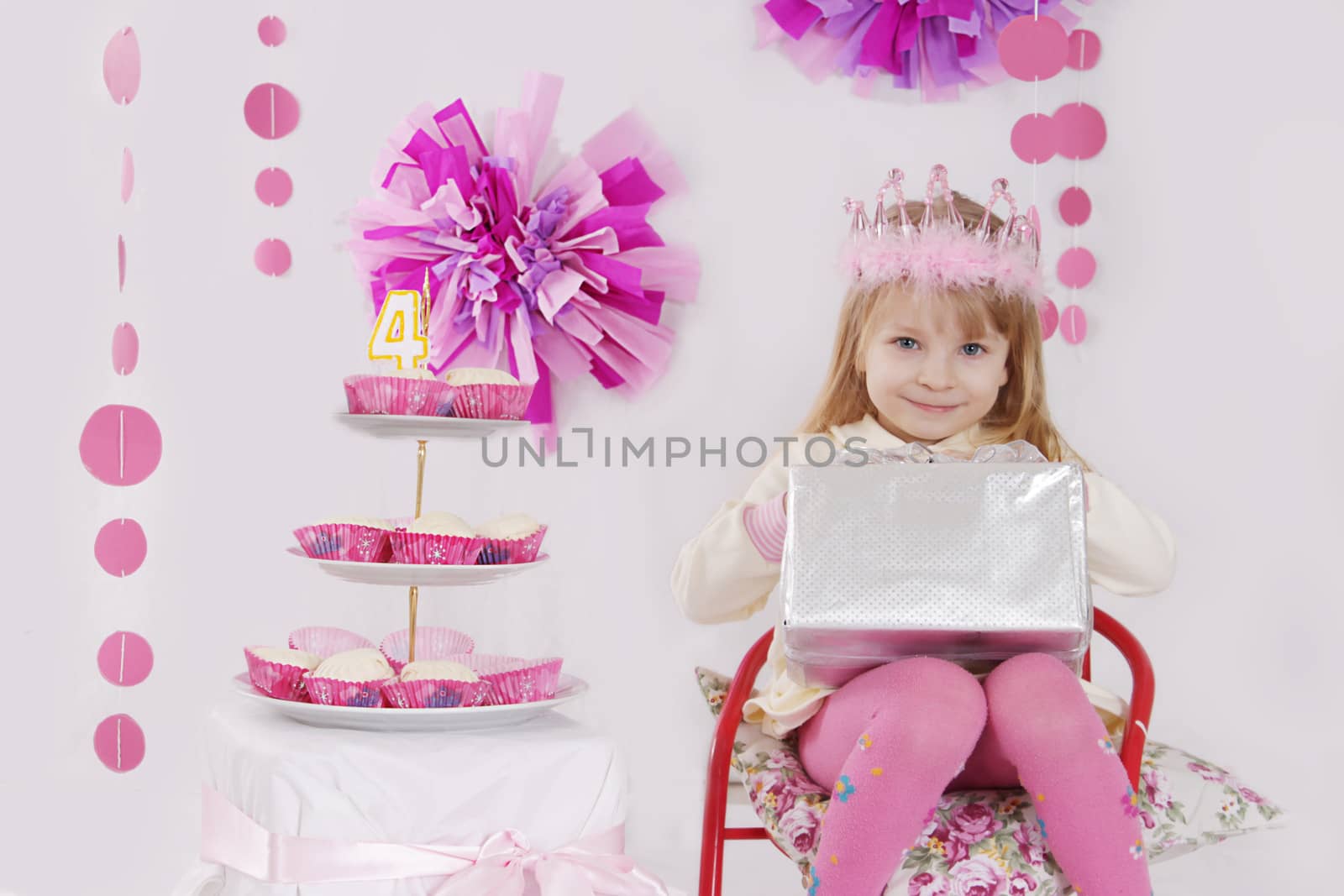 Little girl with present at pink decoration birthday party