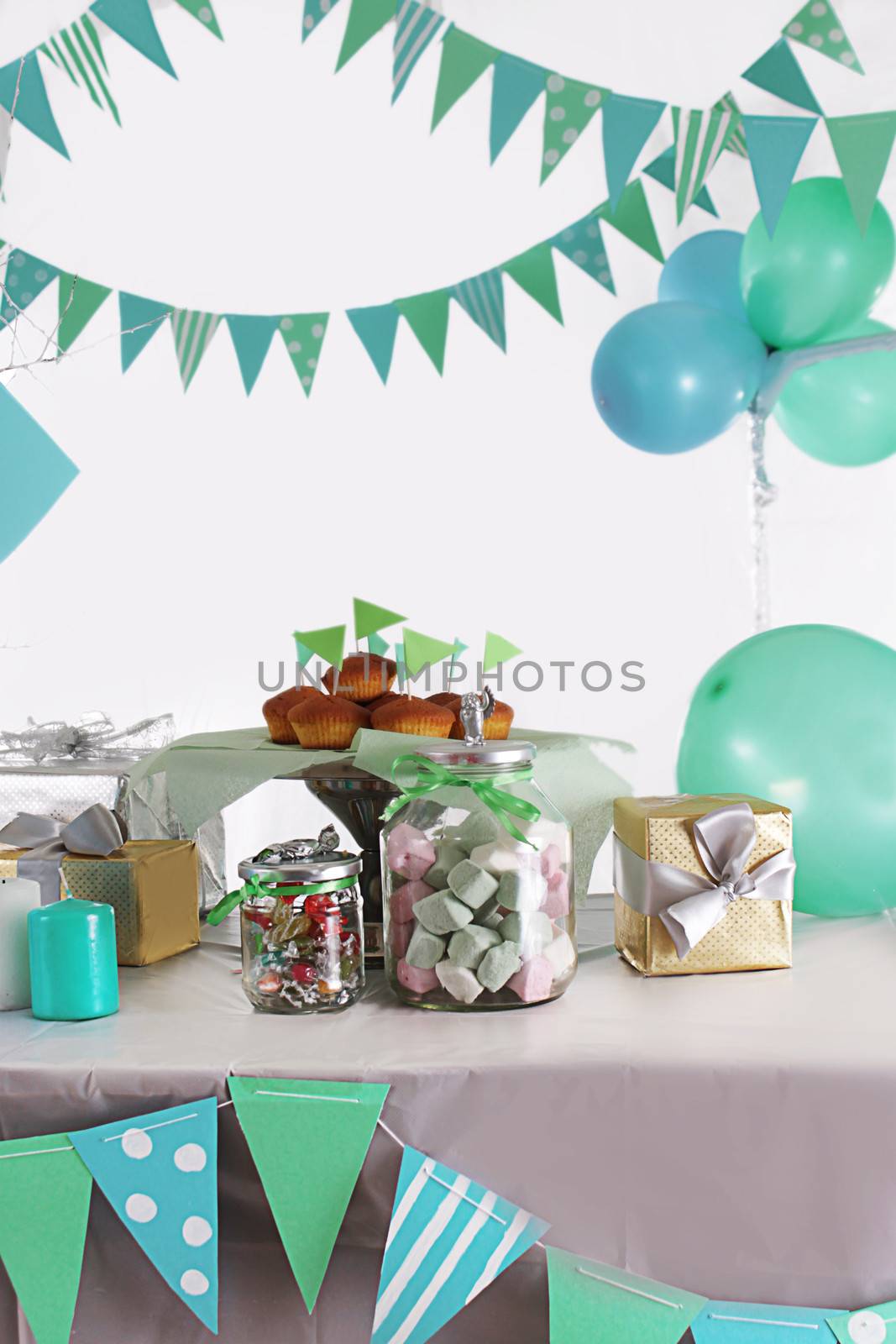 Blue and green colored birthday party table with sweets and decorations
