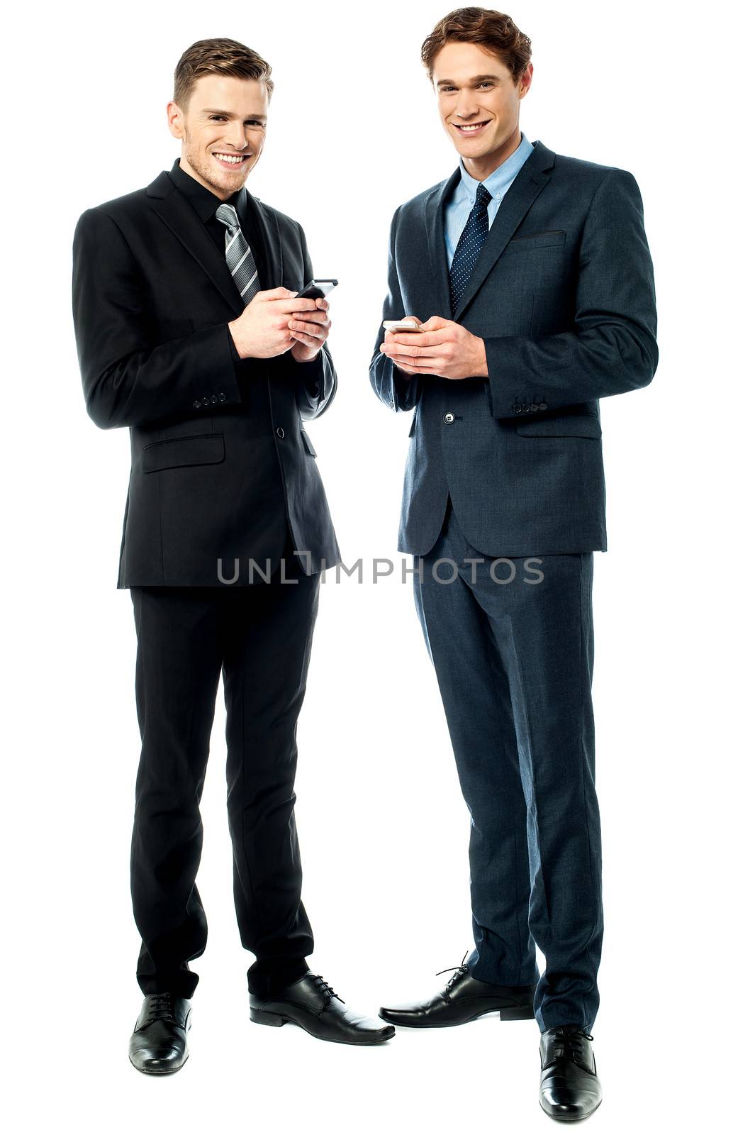 Happy businessmen using cellphone by stockyimages