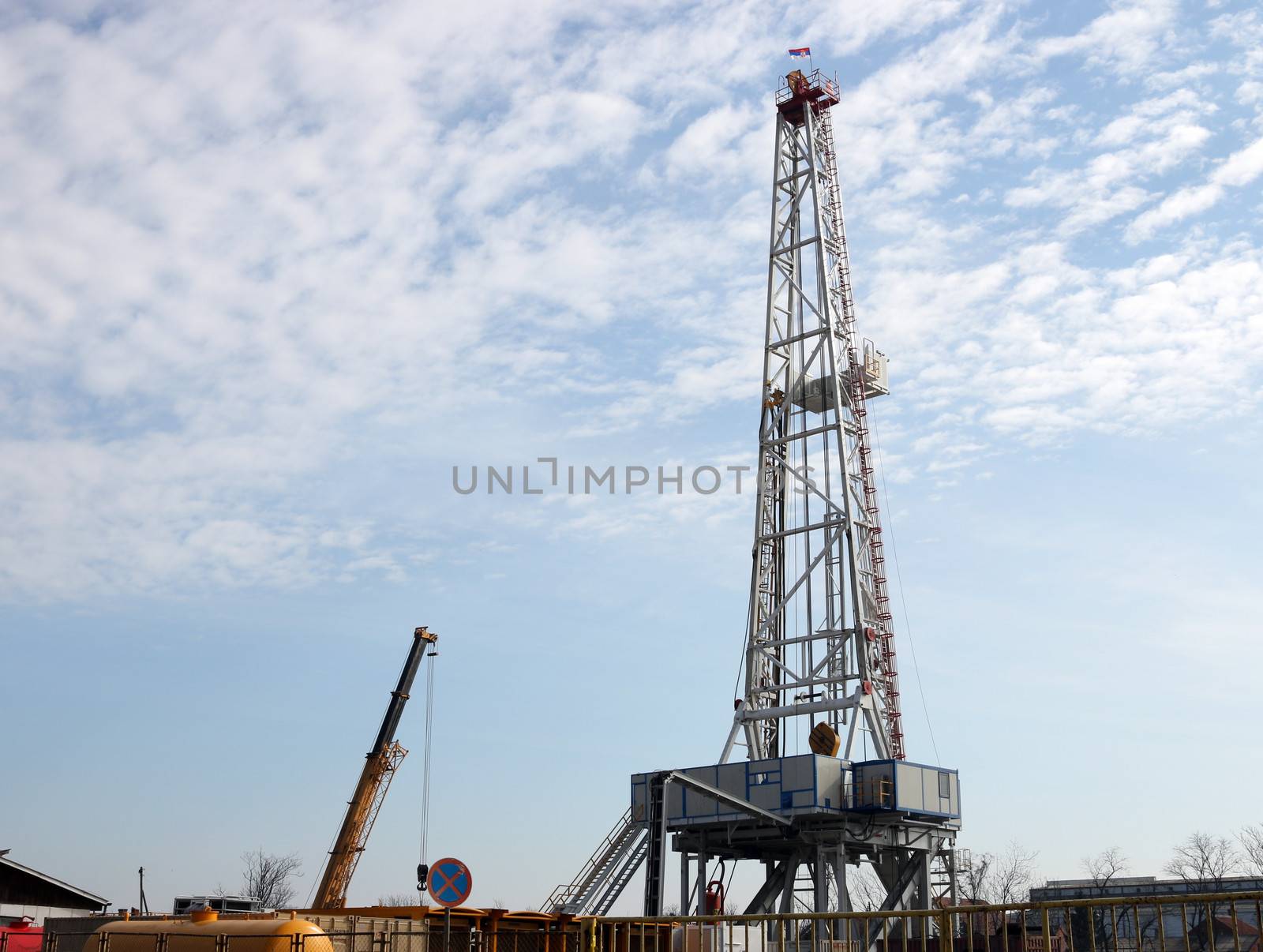 oil drilling rig and crane on field by goce