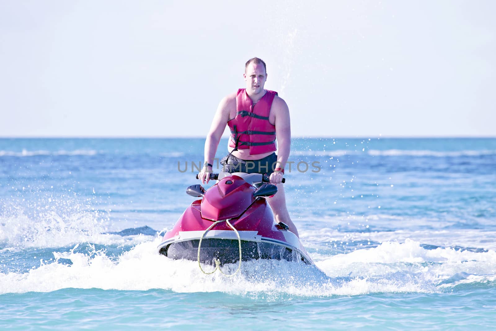 Young guy cruising in the caribbean sea on a jet ski