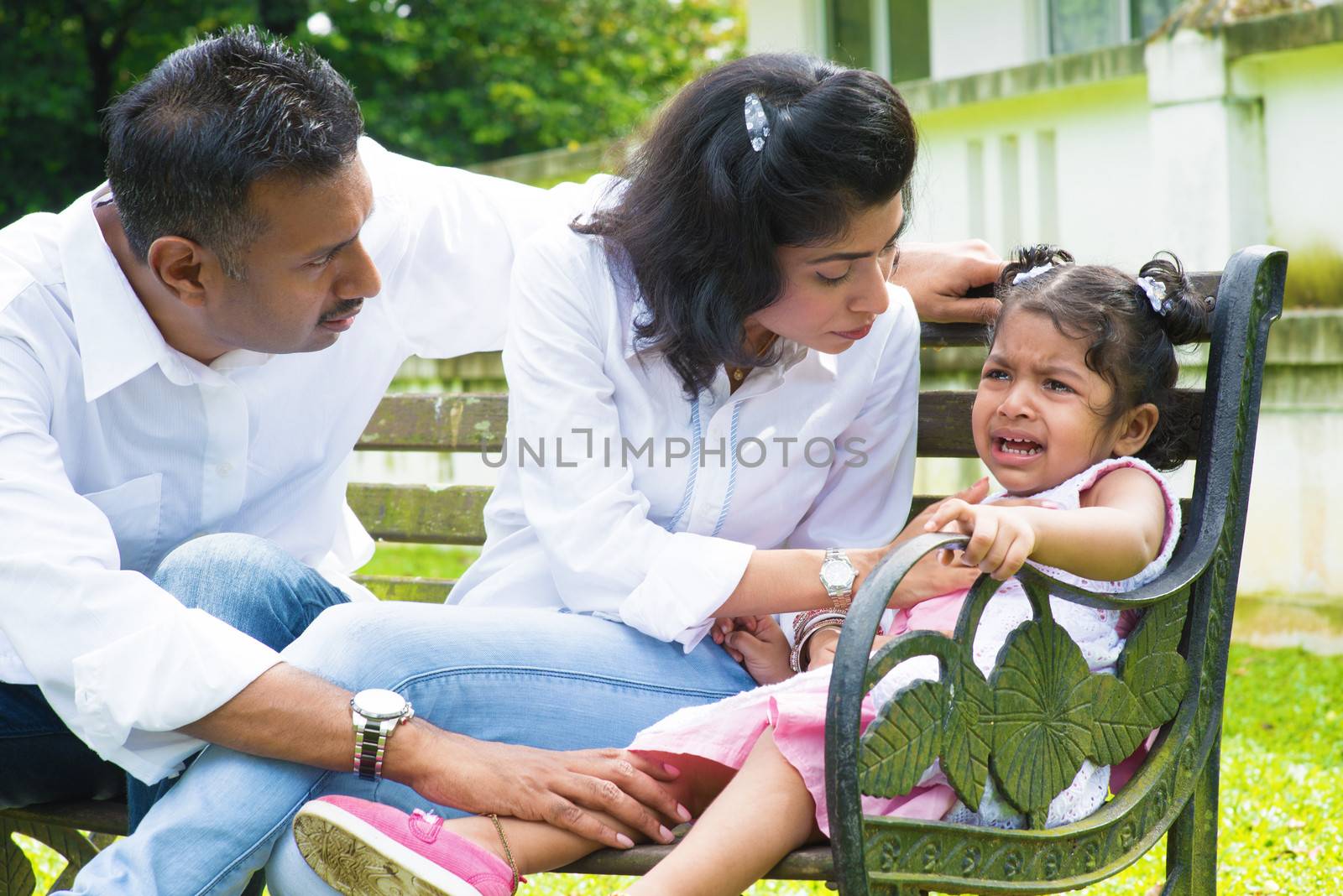 Indian family outdoor. Parents is comforting their crying daughter.
