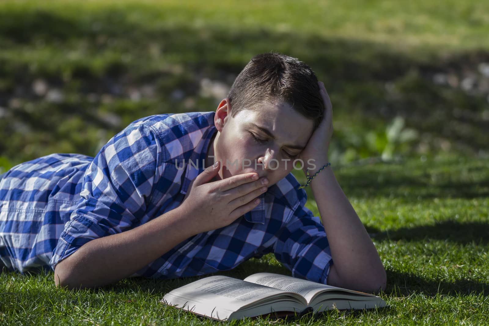 Young boy reading a book in the woods with shallow depth of fiel by FernandoCortes