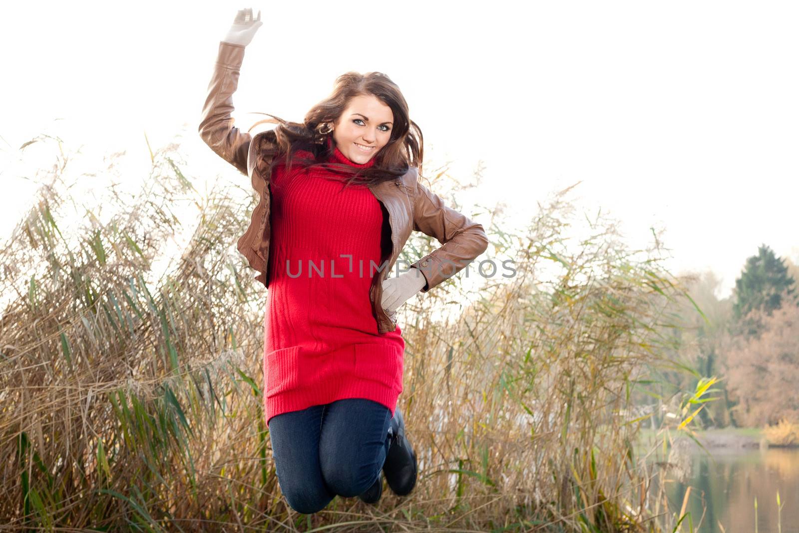 Happy brunette is having a nice time in the park while it's autumn