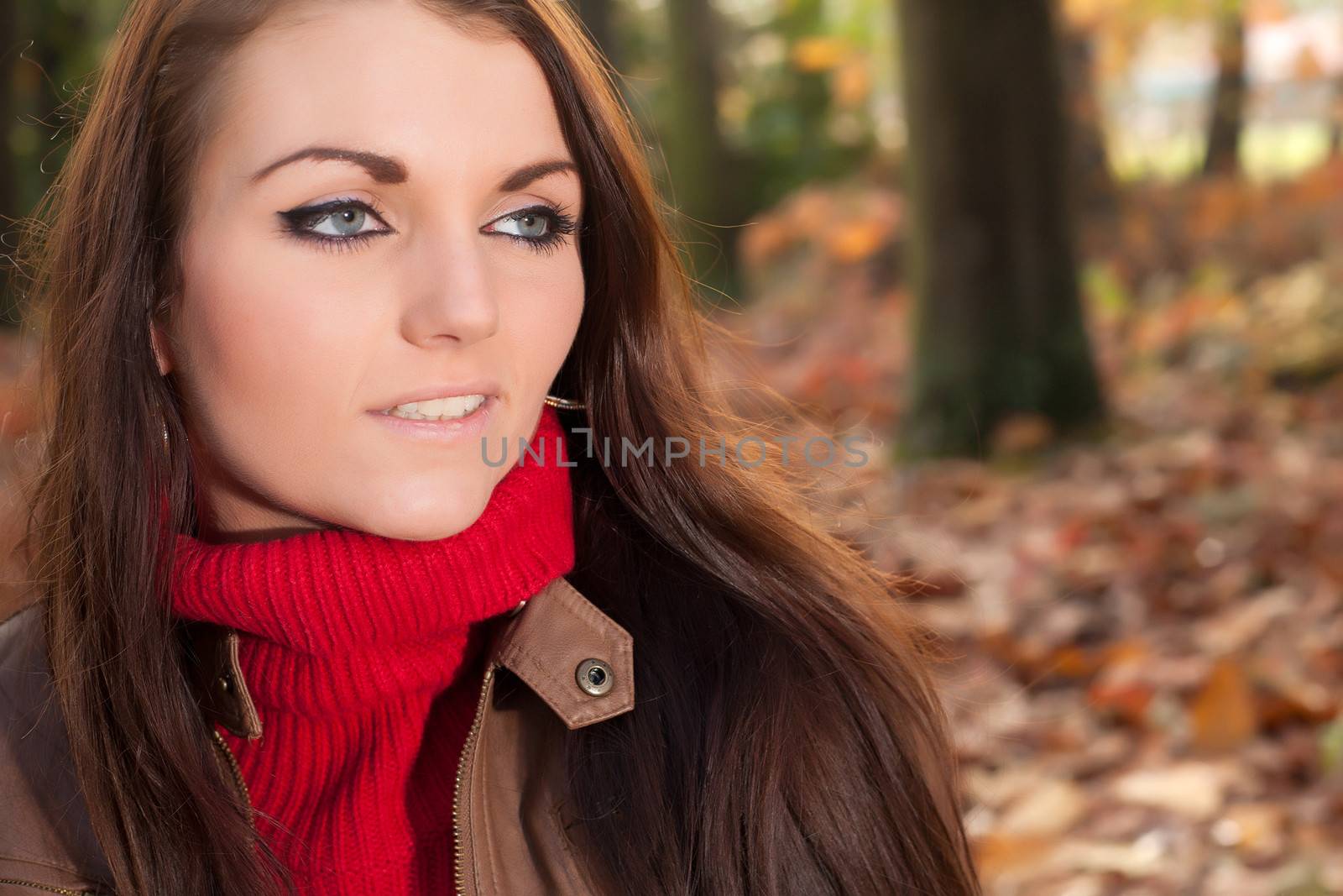 Happy brunette is having a nice time in the park while it's autumn