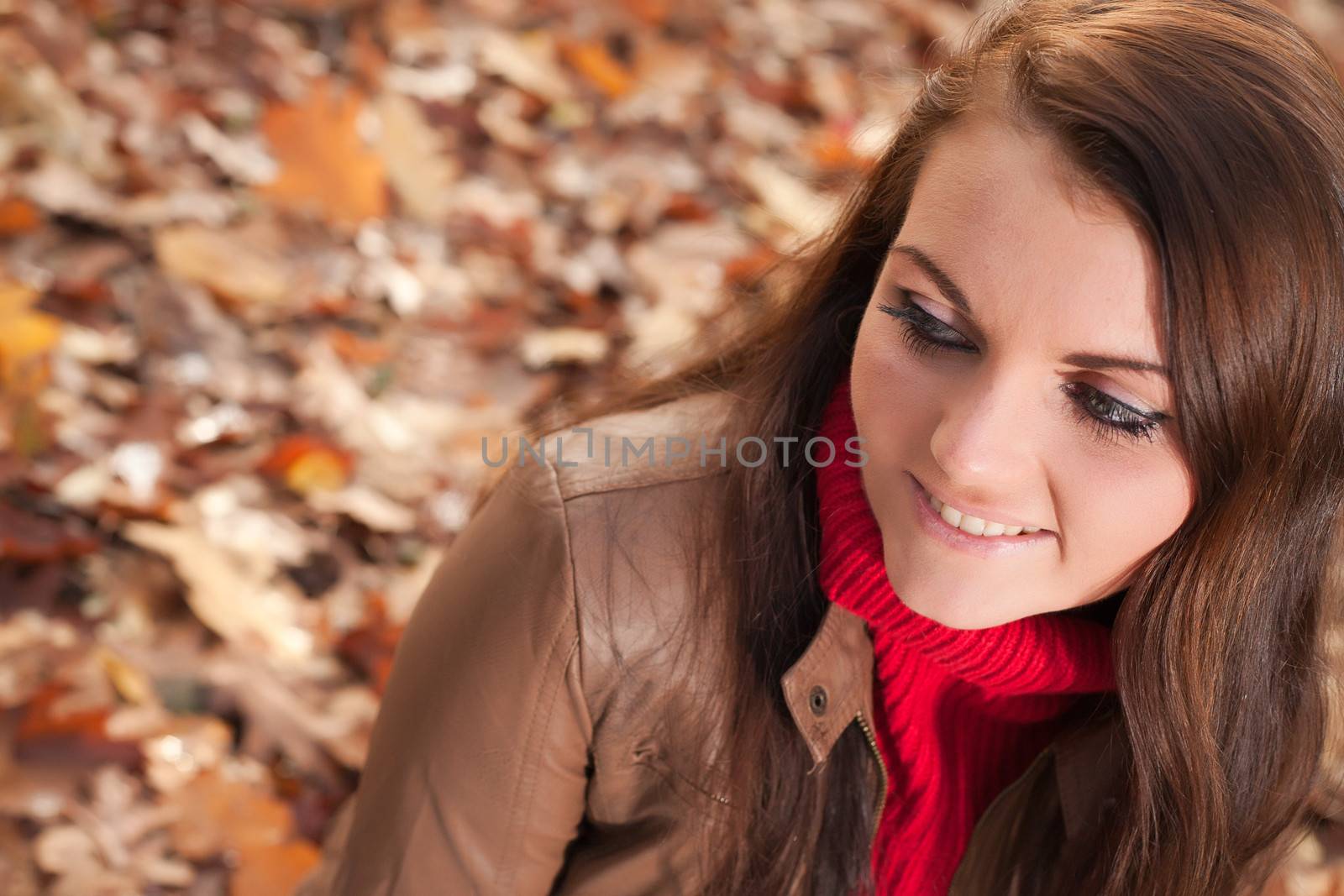 Happy brunette is having a nice time in the park while it's autumn