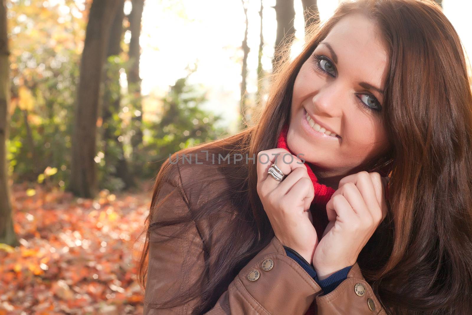 Happy brunette is having a nice time in the park while it's autumn