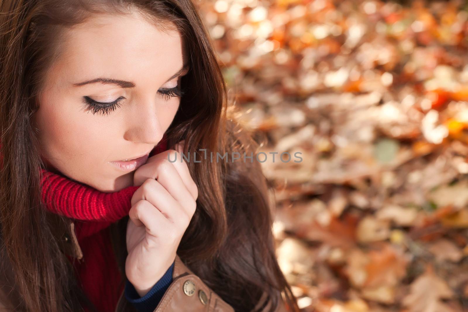 Happy brunette is having a nice time in the park while it's autumn