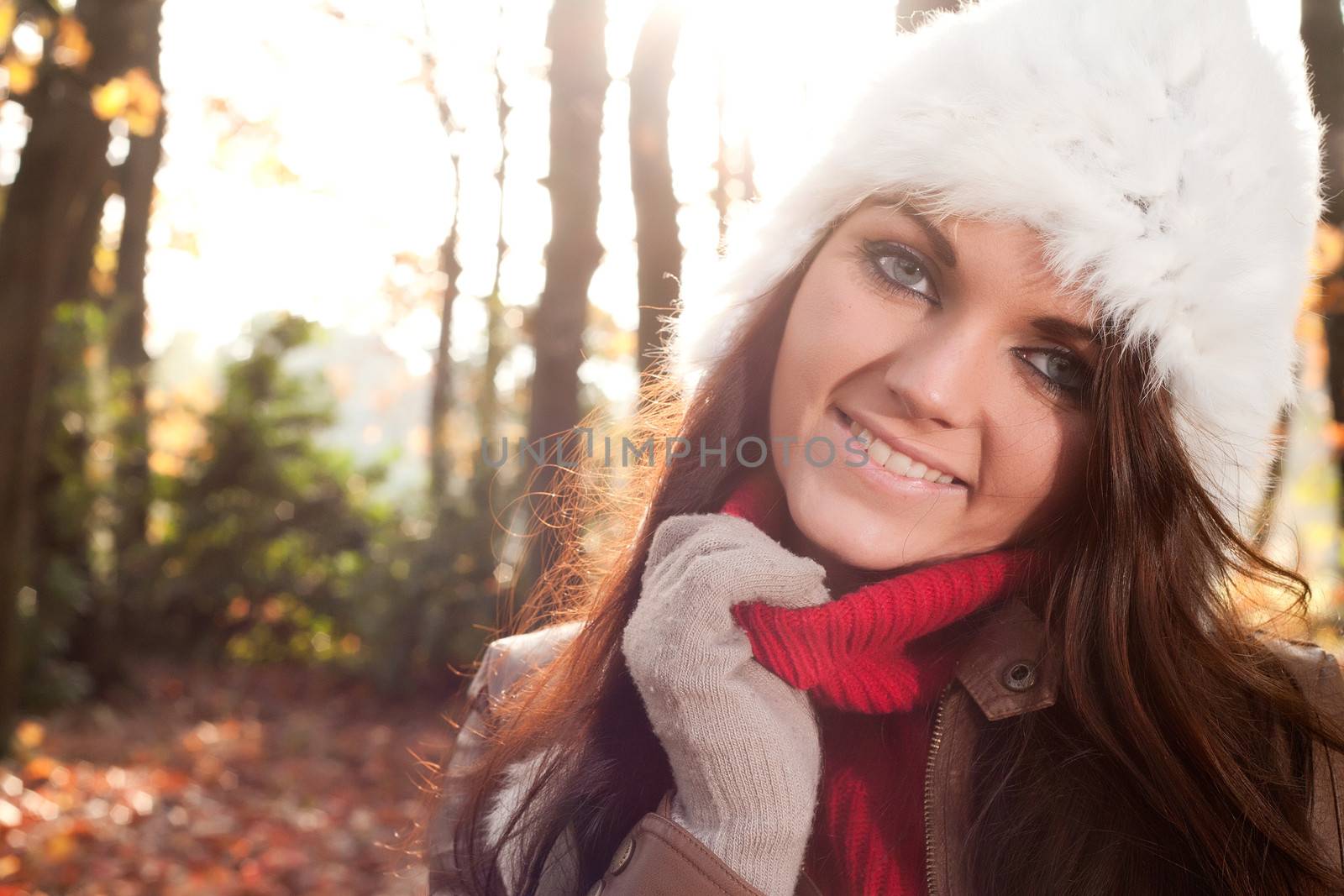 Happy brunette is having a nice time in the park while it's autumn