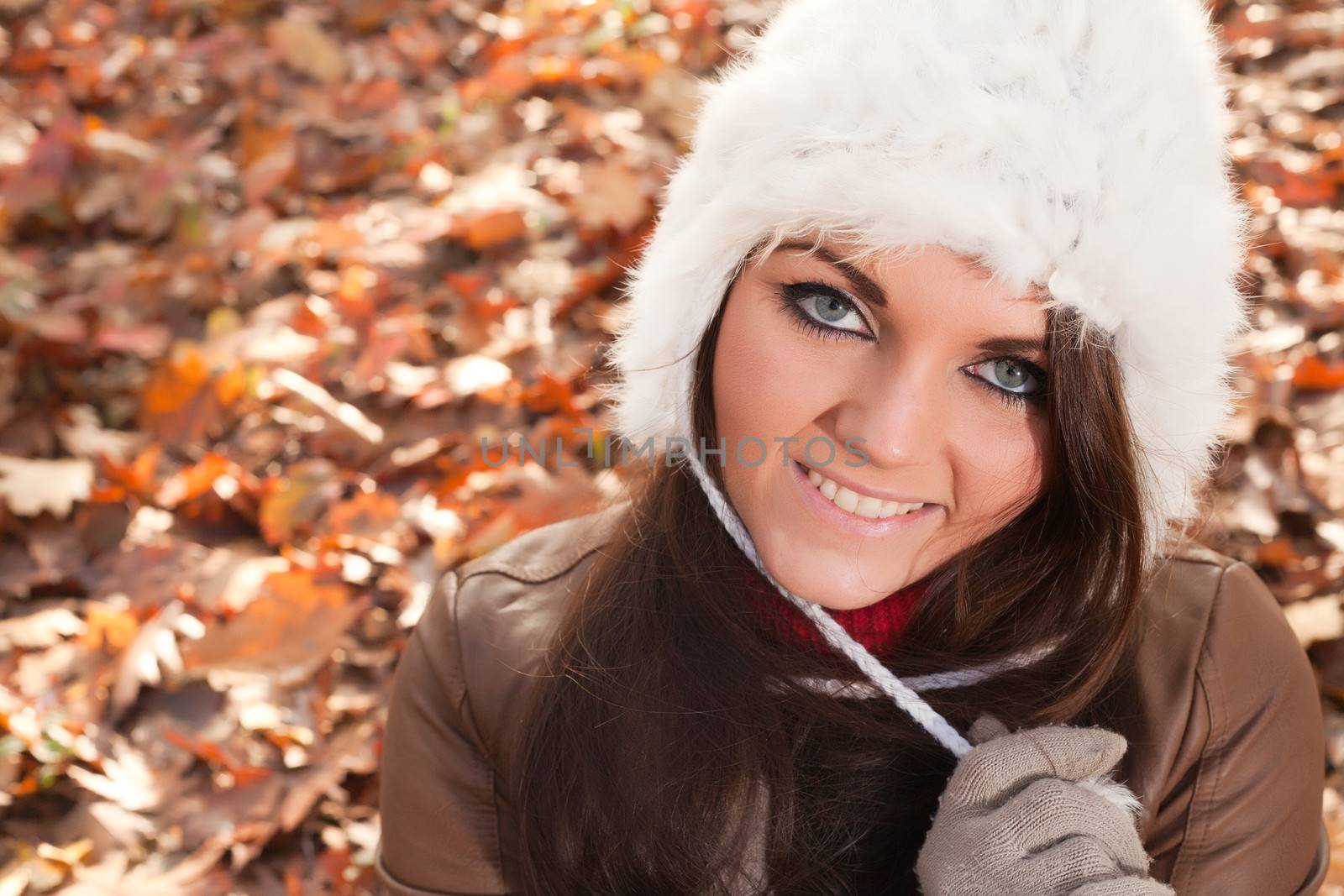 Happy brunette is having a nice time in the park while it's autumn