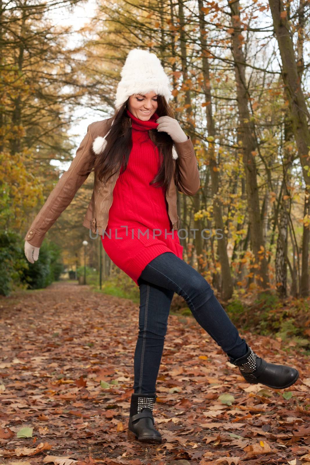 Happy brunette is having a nice time in the park while it's autumn