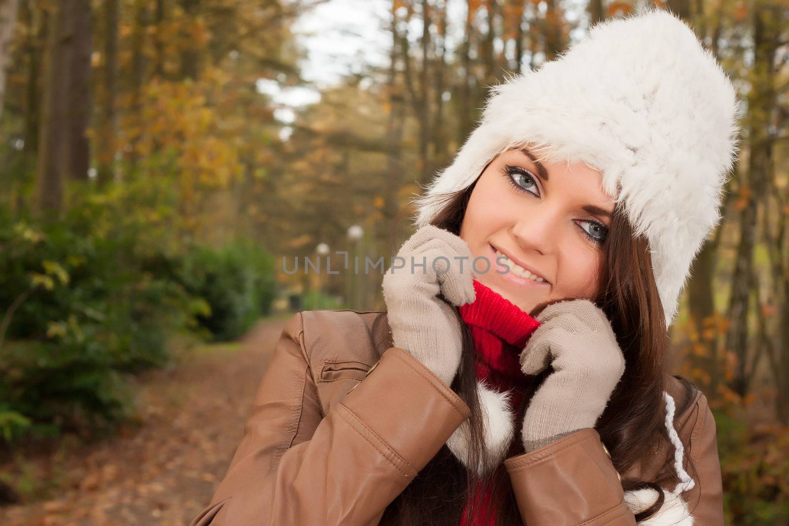 Happy brunette is having a nice time in the park while it's autumn