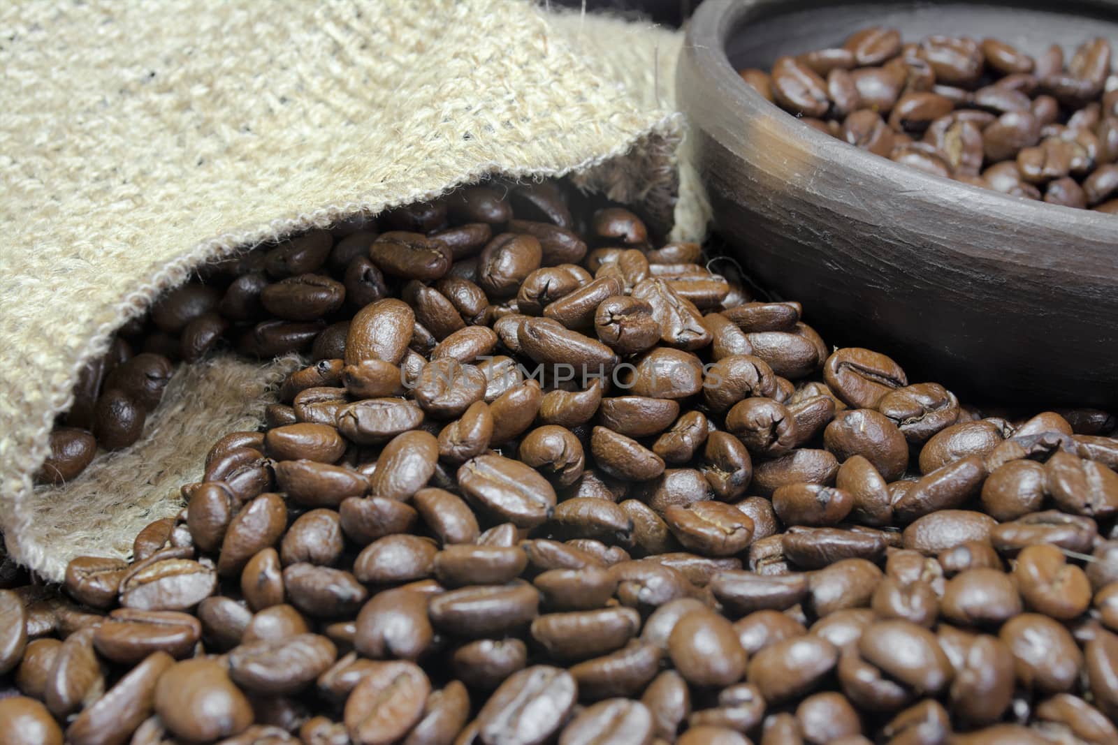 Detail of coffee beans, small clay pot and jute bag with front lighting