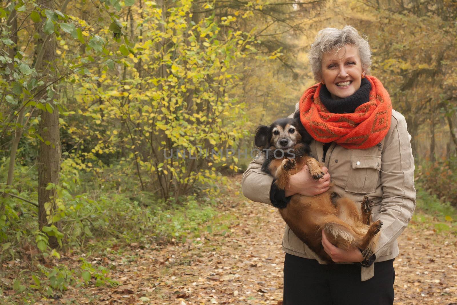 Middle aged woman in the autumn forest with her dog