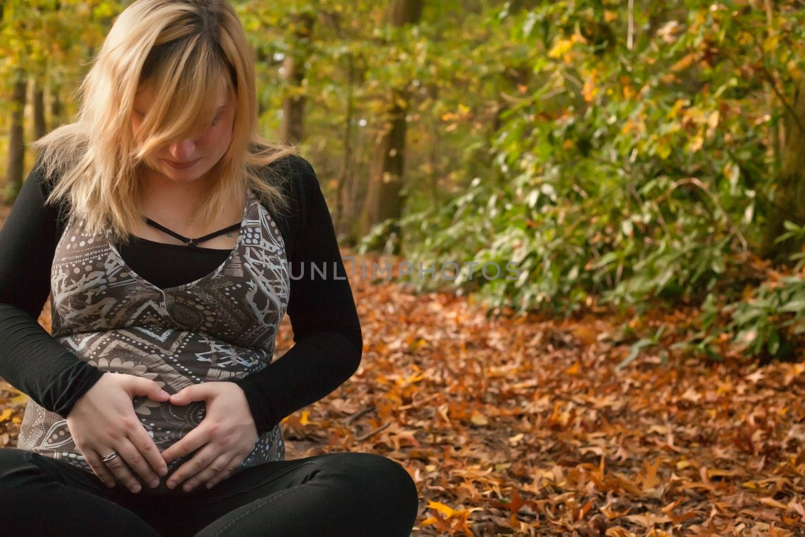 Blond young girl is waiting for her little child. Shoot in the forest