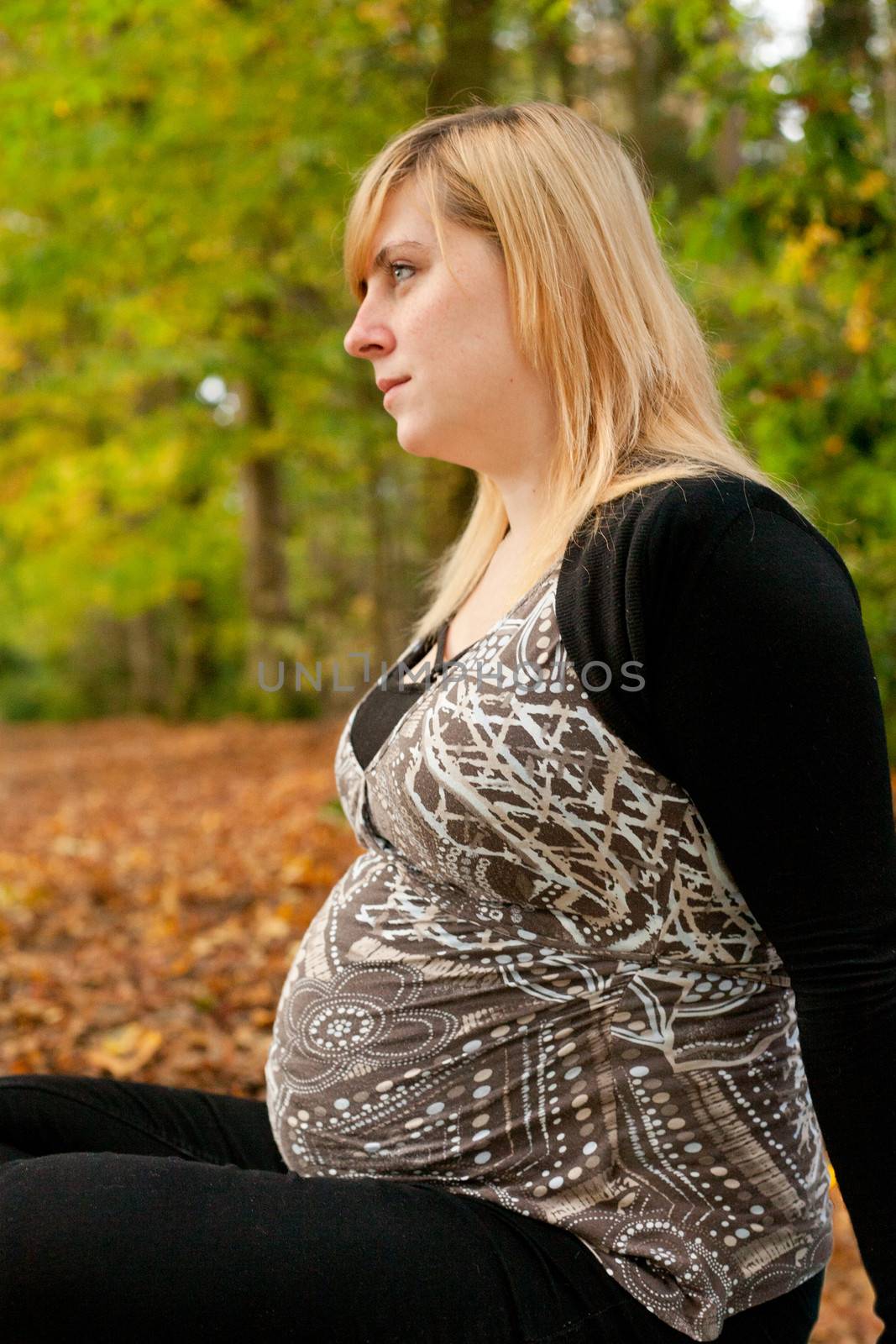 Blond young girl is waiting for her little child. Shoot in the forest