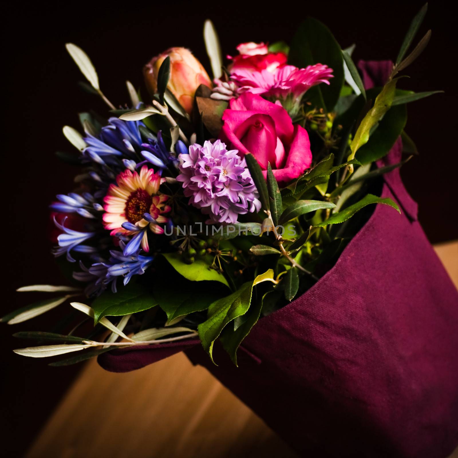 Vase like a shopping bag filled with spring flowers and with dark background - square image