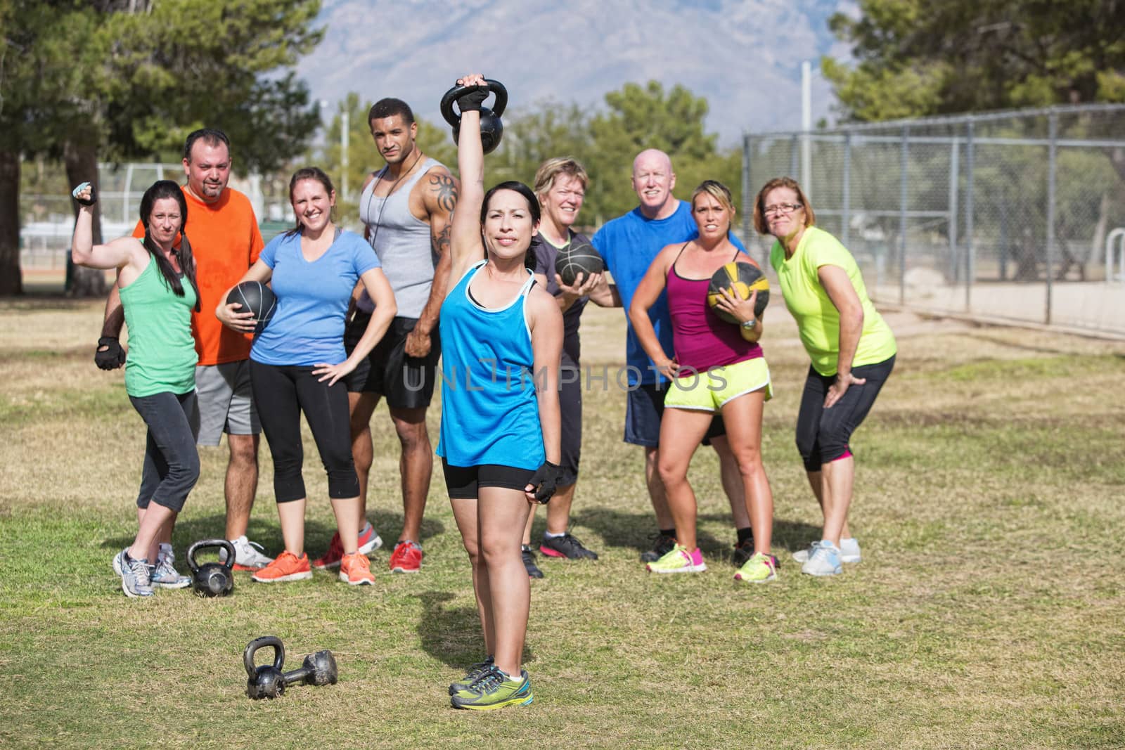Happy woman lifting weights with group outdoors
