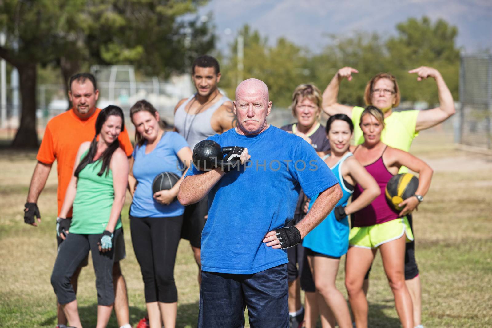 Serious middle aged man with weights and fitness group