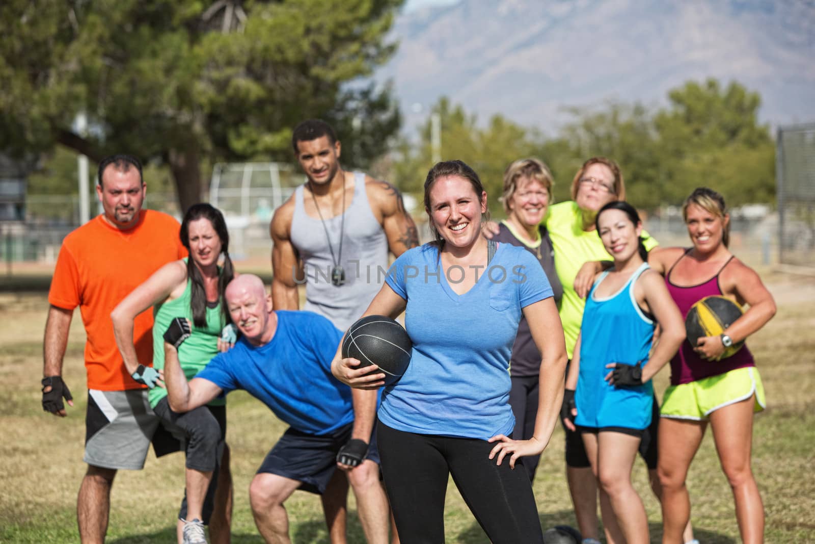 Smilng woman and boot camp fitness group with medicine ball