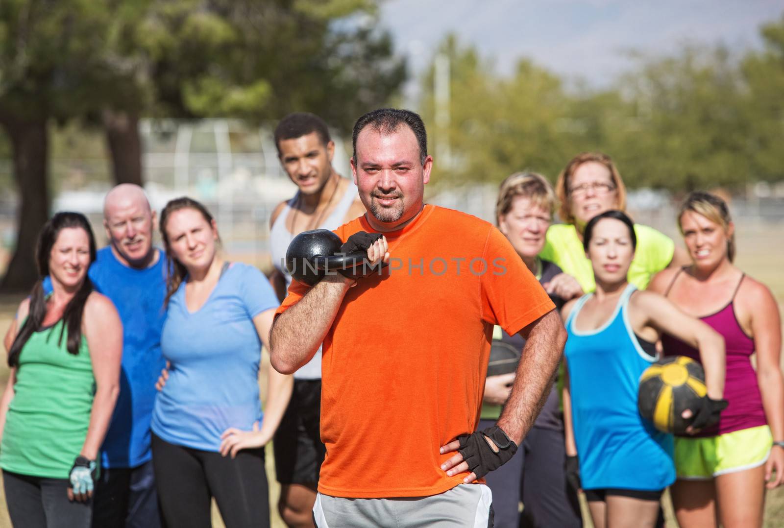 Group watching man hold kettle bell weights