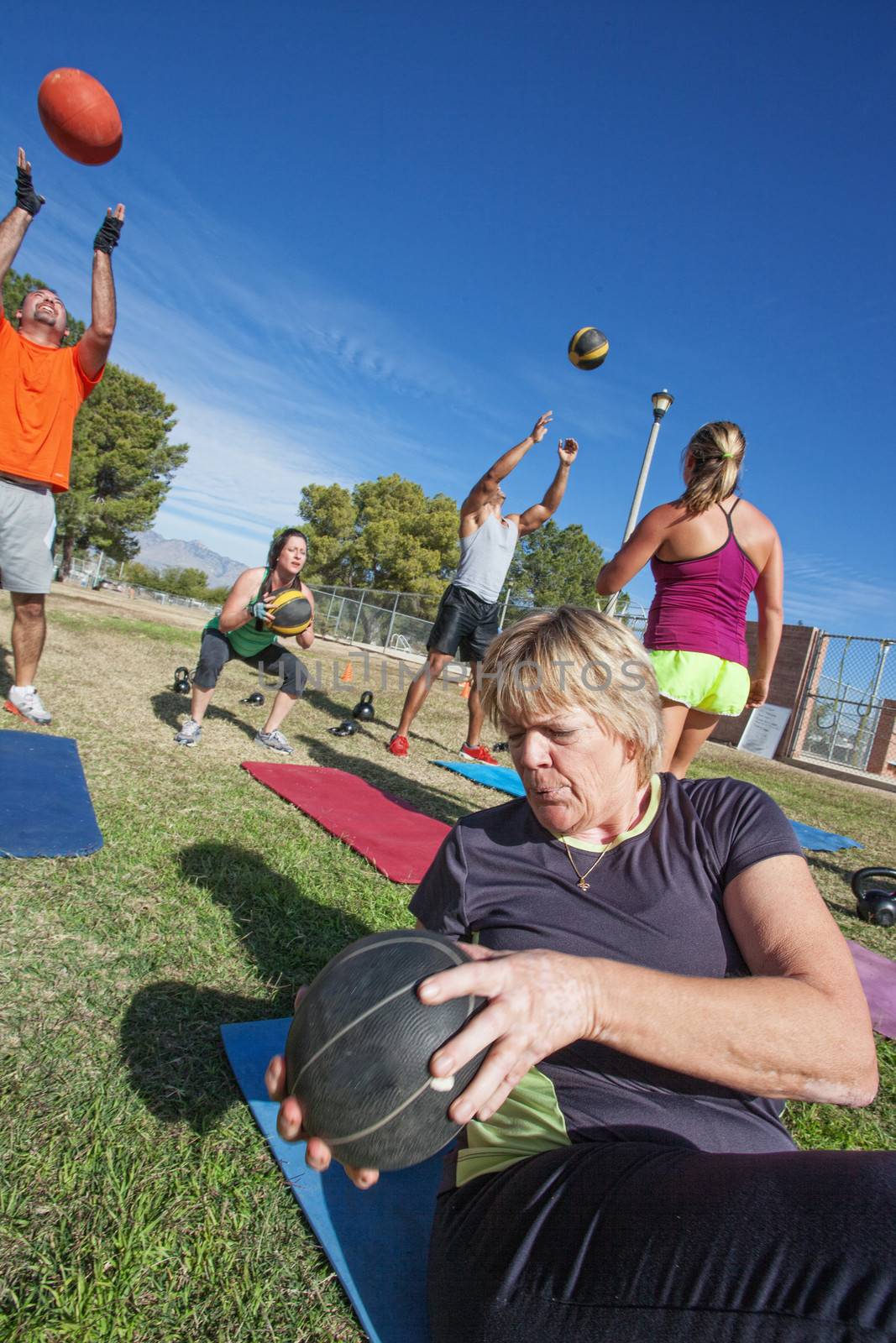 Diverse boot camp fitness class exercising outdoors