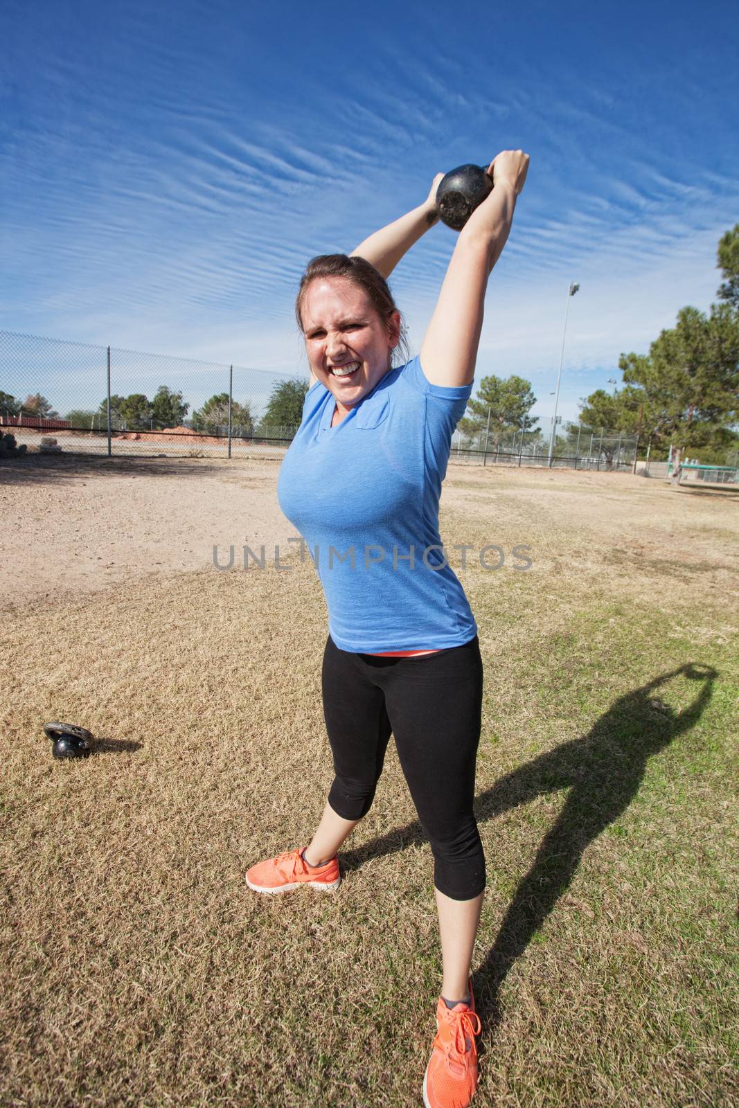 Enthusiastic Caucasian woman exercising with kettle bell weight outdoors