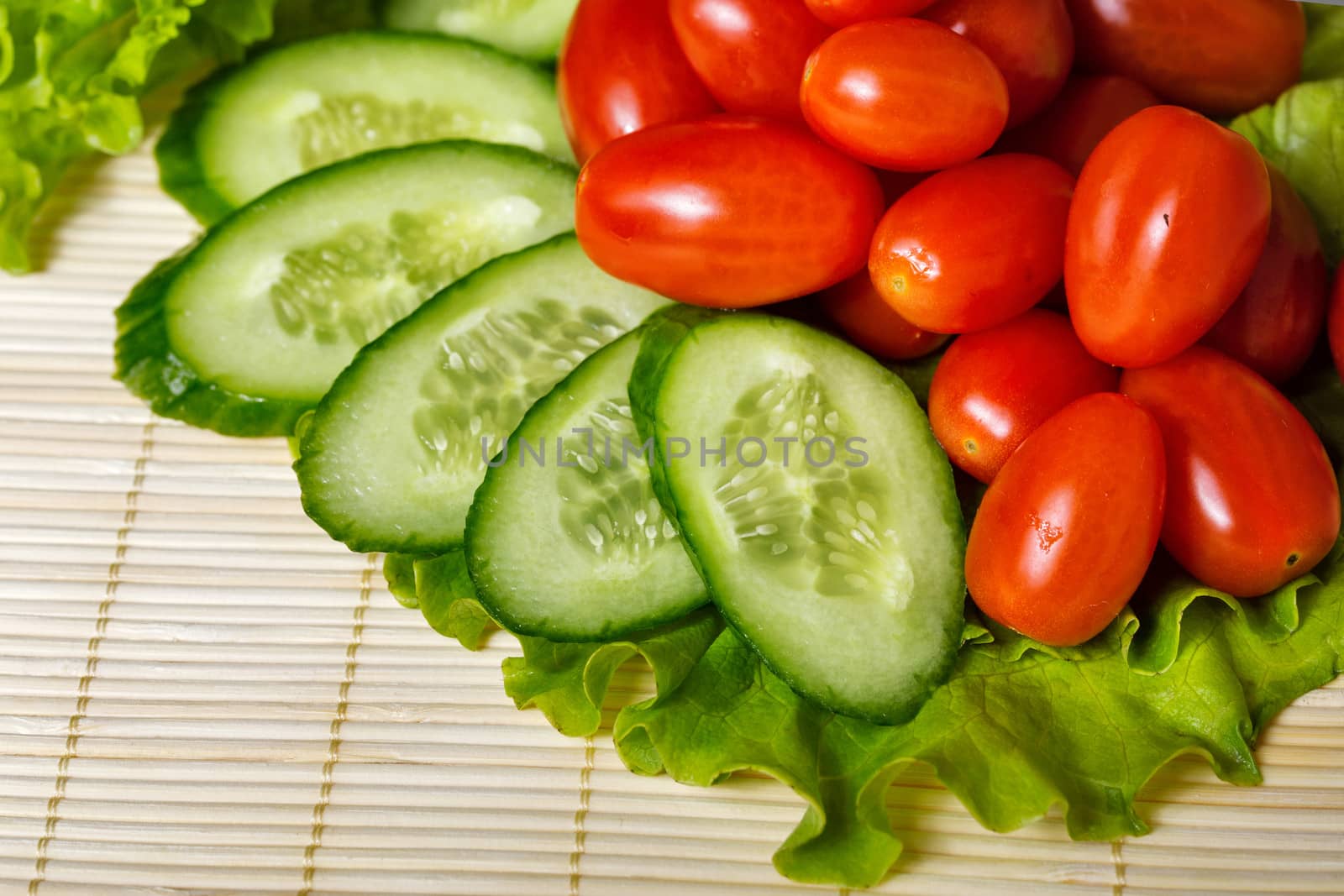 Ripe cherry tomatoes, cucumbers and lettuce closeup shot