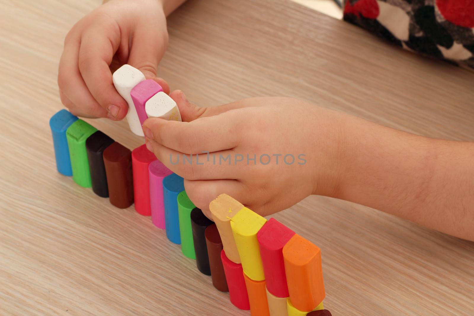 child play with colorful plasticine blocks by goce