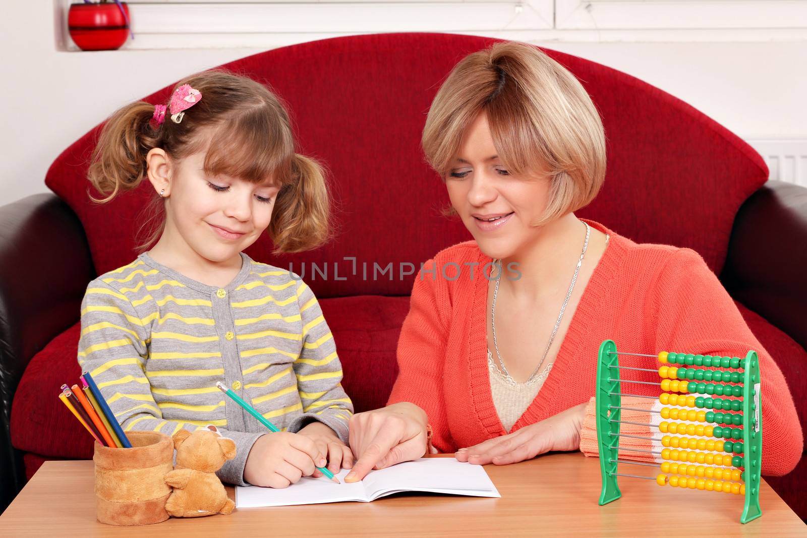 happy mother and daughter doing homework by goce