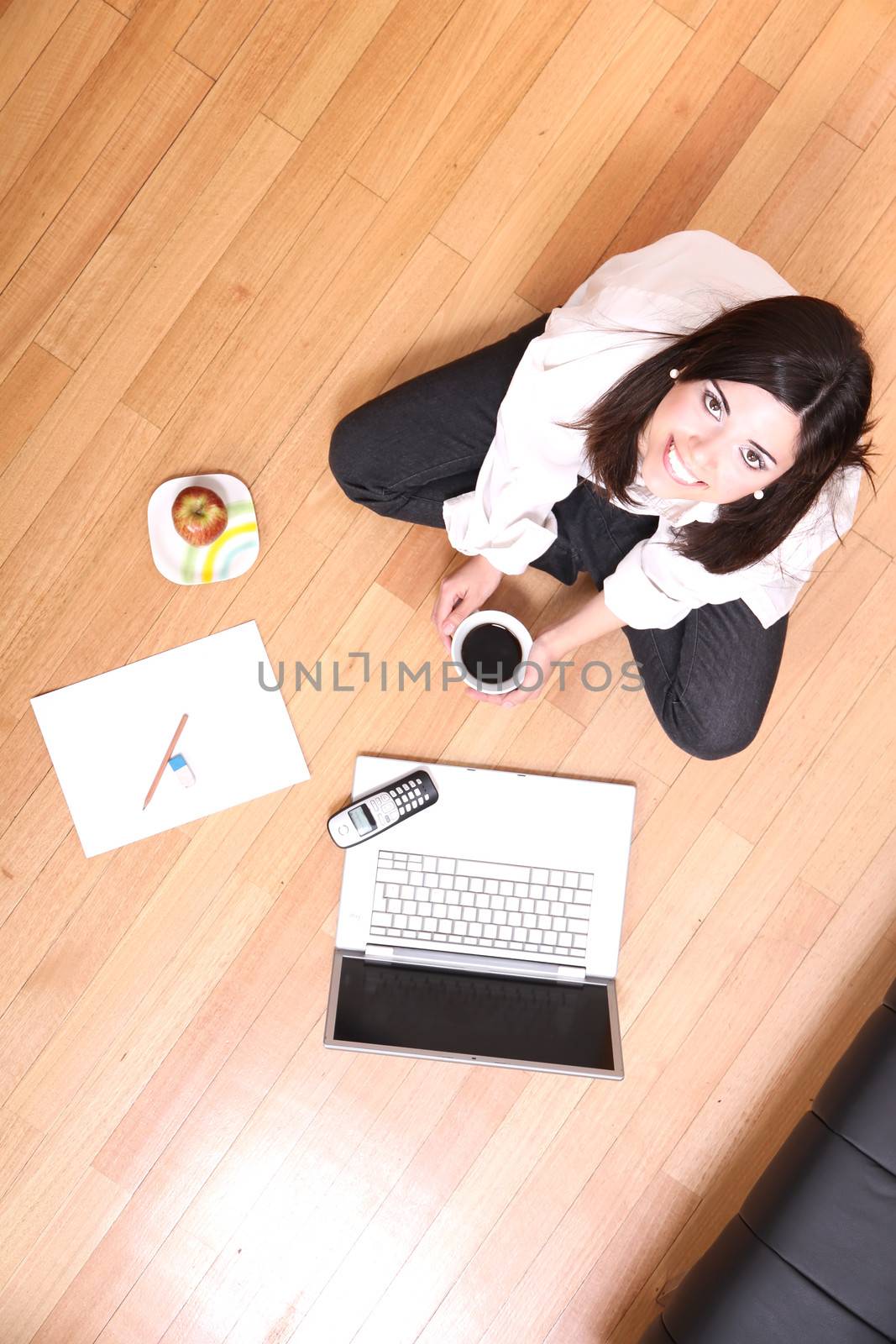 A young adult woman studying on the floor.