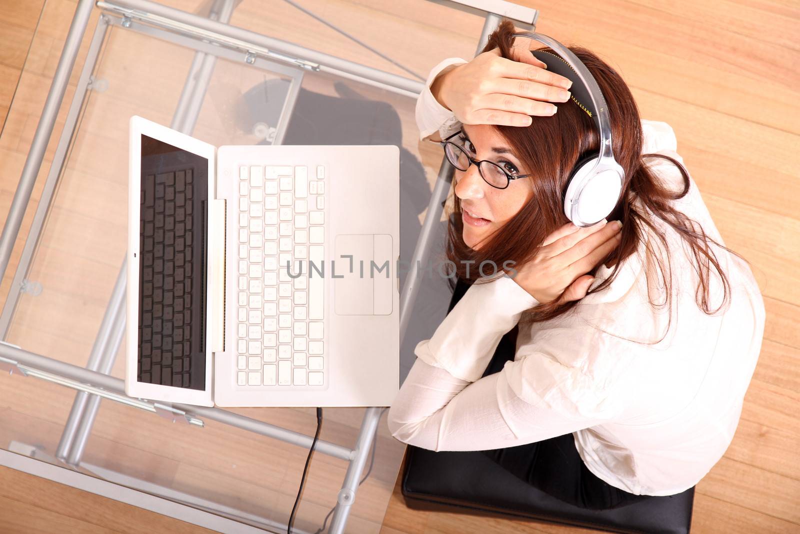 Business woman working on a Laptop while listening music with Headphones.