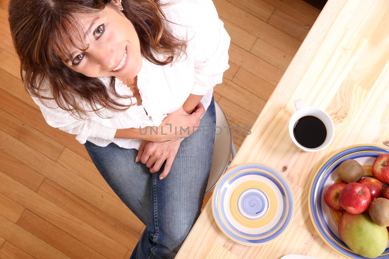 Portrait of a beautiful mature woman sitting in the kitchen. Focus on the Table.