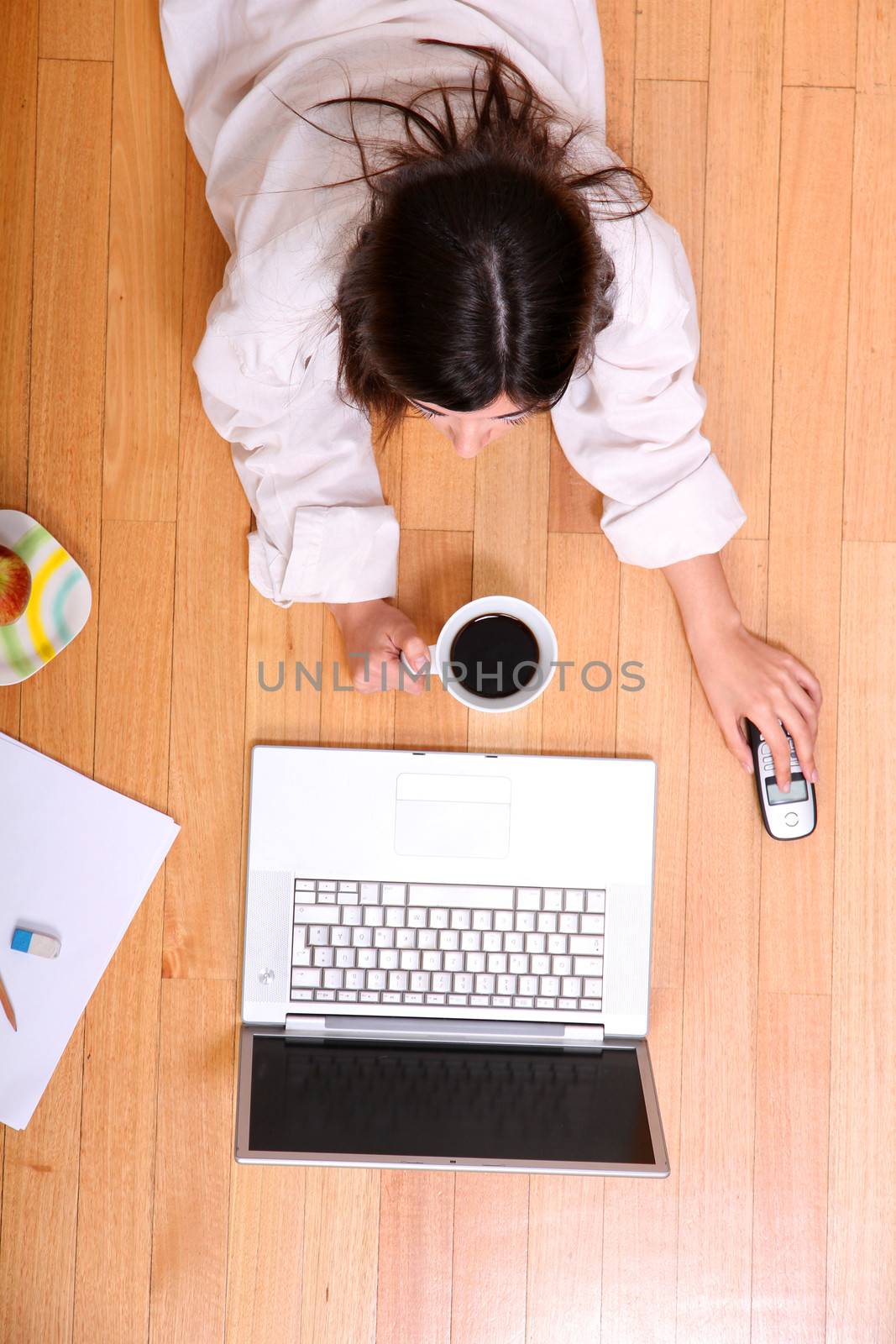 A young adult woman studying on the floor.