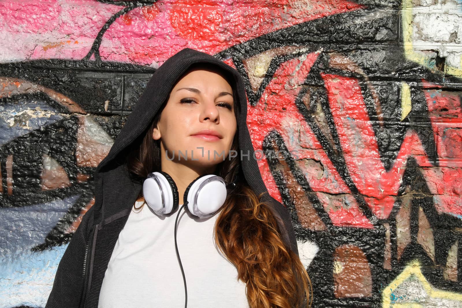 A young woman enjoying the Sunlight leaning against a wall.
