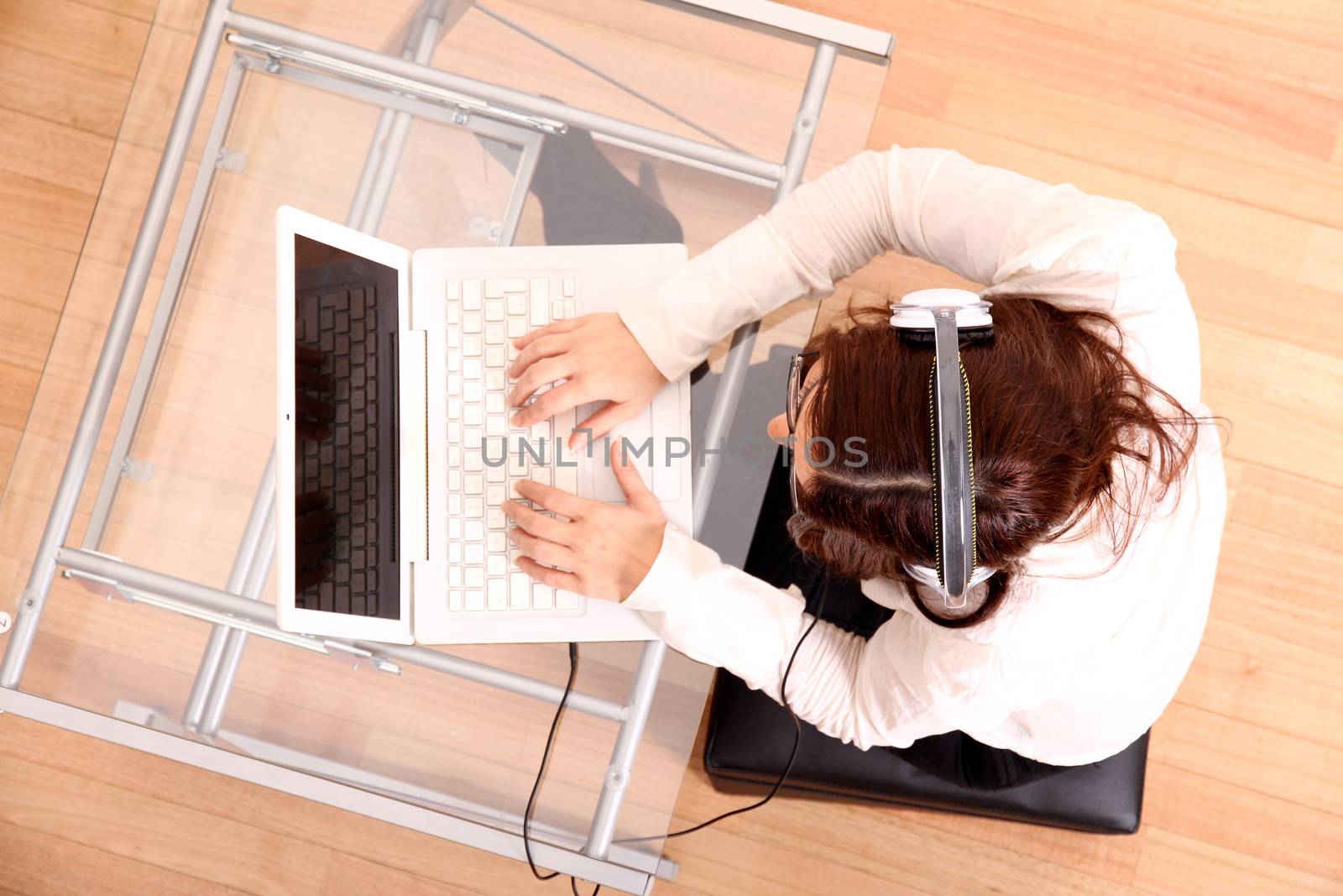 Business woman working on a Laptop while listening music with Headphones.