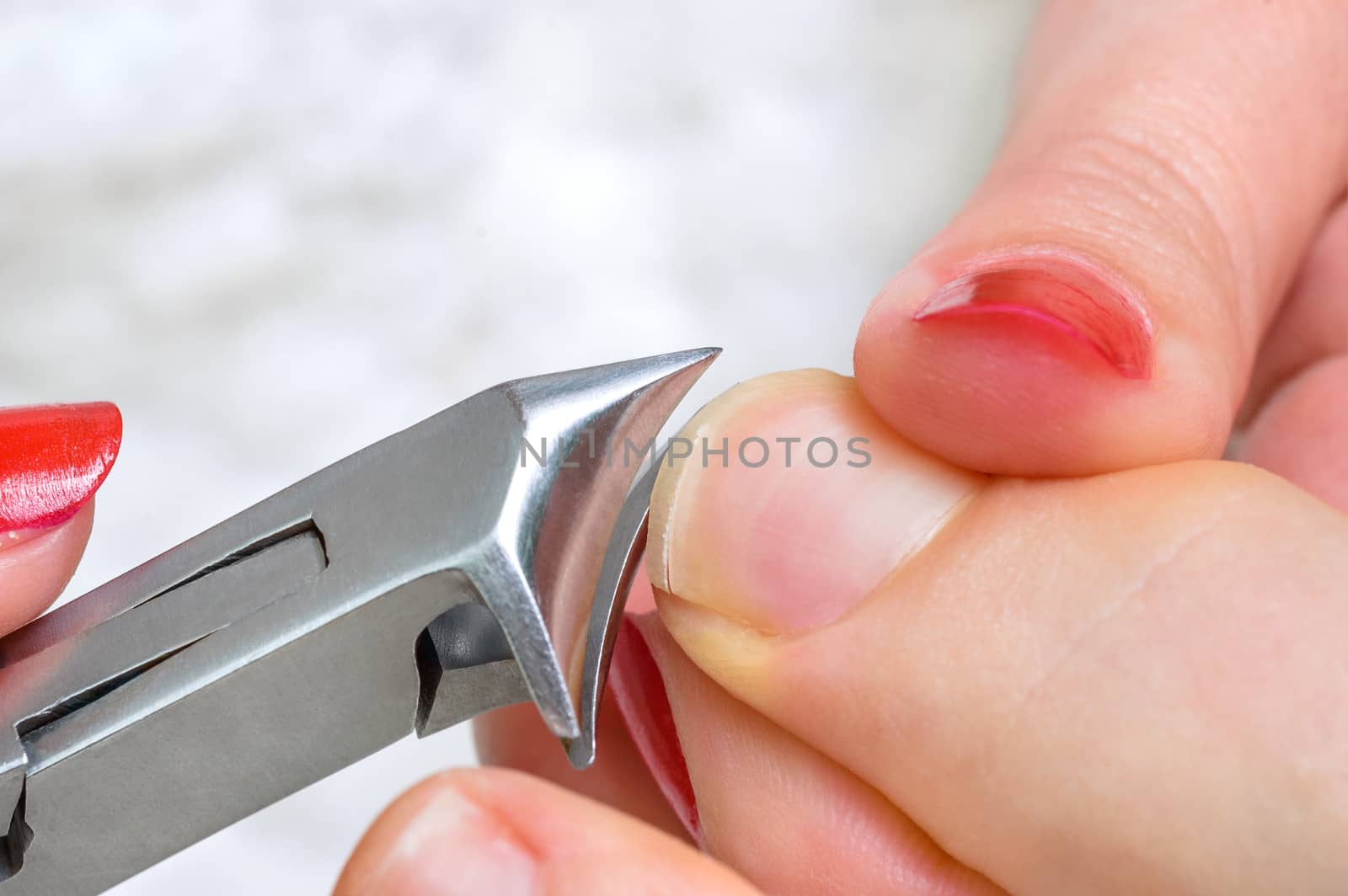 cutting fingernail with clipper in process, female hand