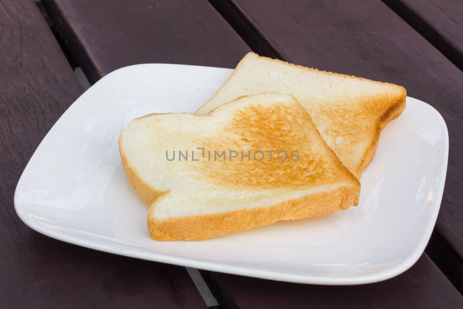 two toasts in white dish on brown table