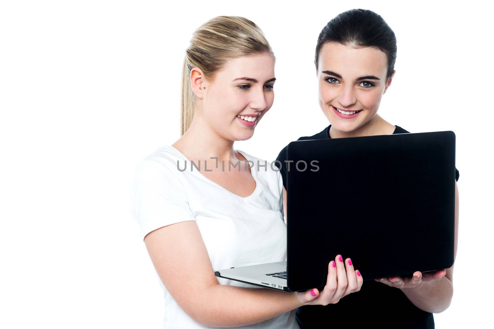 Happy young female friends using laptop by stockyimages