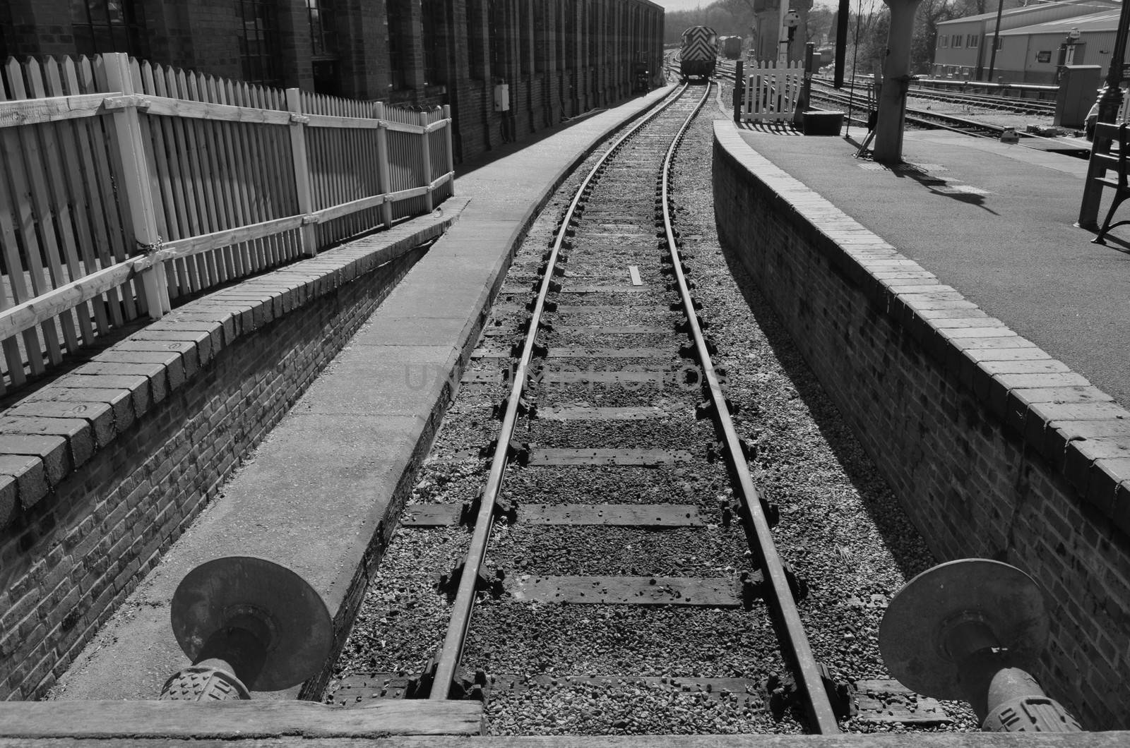 Black and white image of a uk railway siding showing buffers and platform.