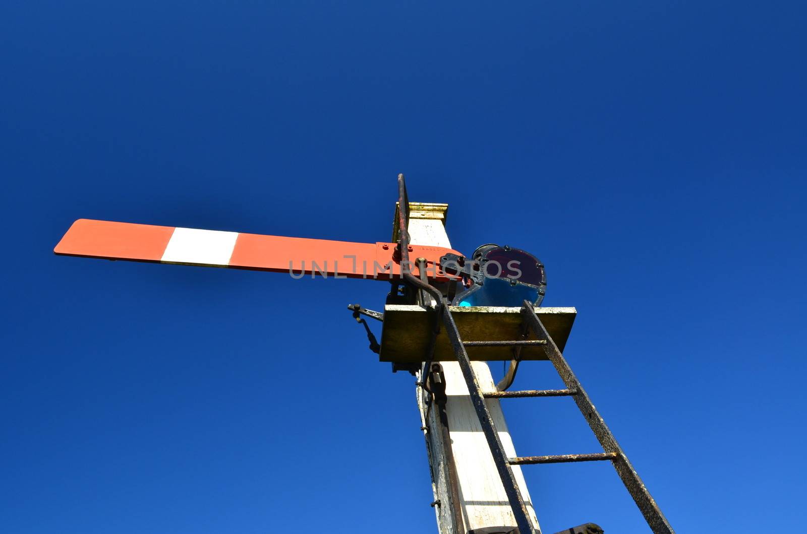 uk railway signal under a clear bright blue sky.