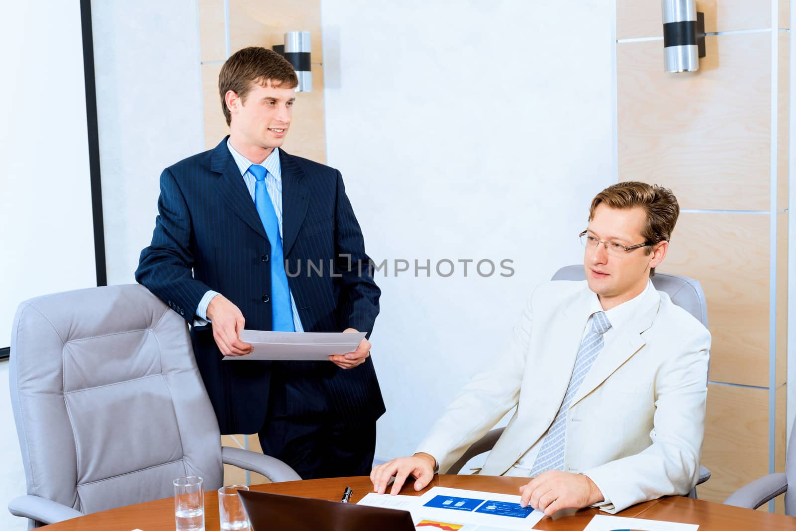 Business people talking, sitting at the table, watching the presentation on a laptop