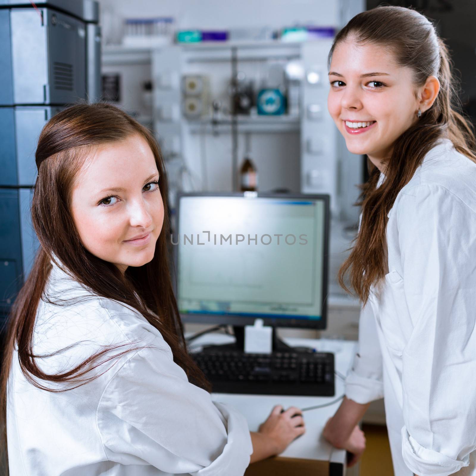 Two chemistry students carrying out experiments in a lab by viktor_cap