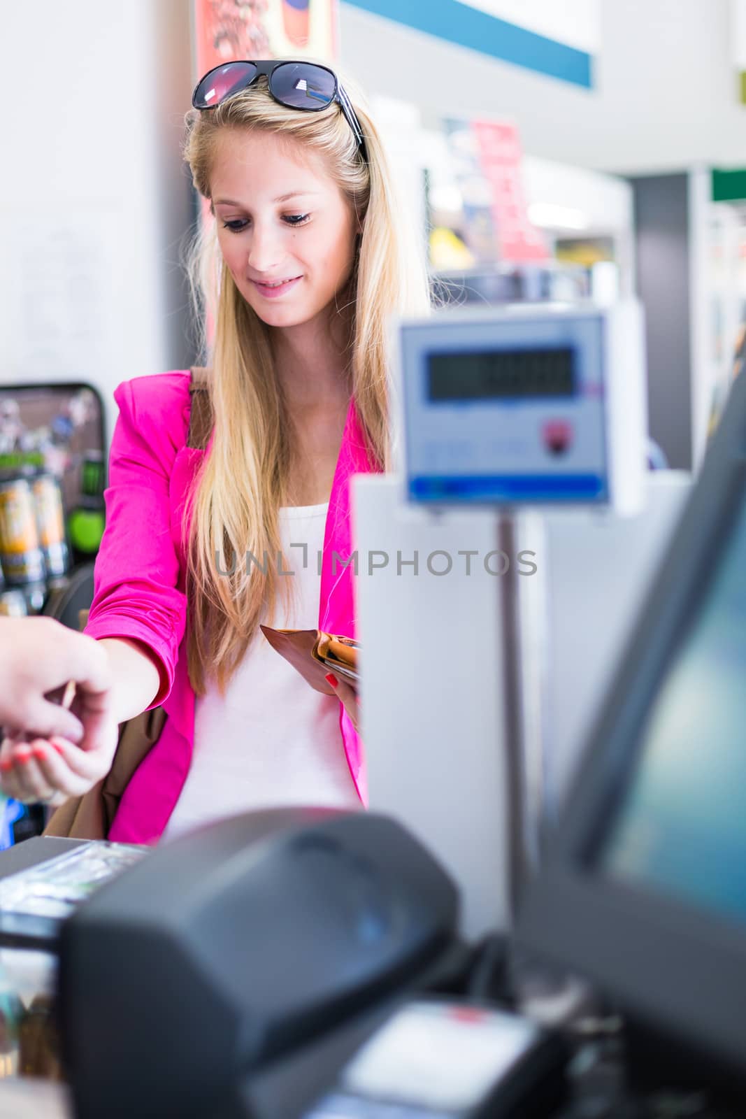 Beautiful young woman paying for her groceries at the counter of a grocery store/supermarket (color toned image)